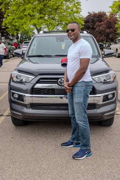 Member in a white T-shirt standing in front of an SUV