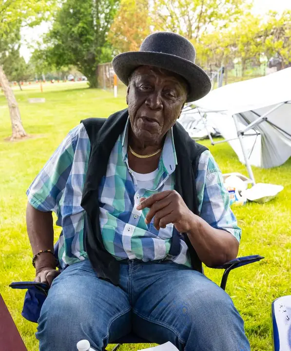 Senior member seated on the sideline in a hat
