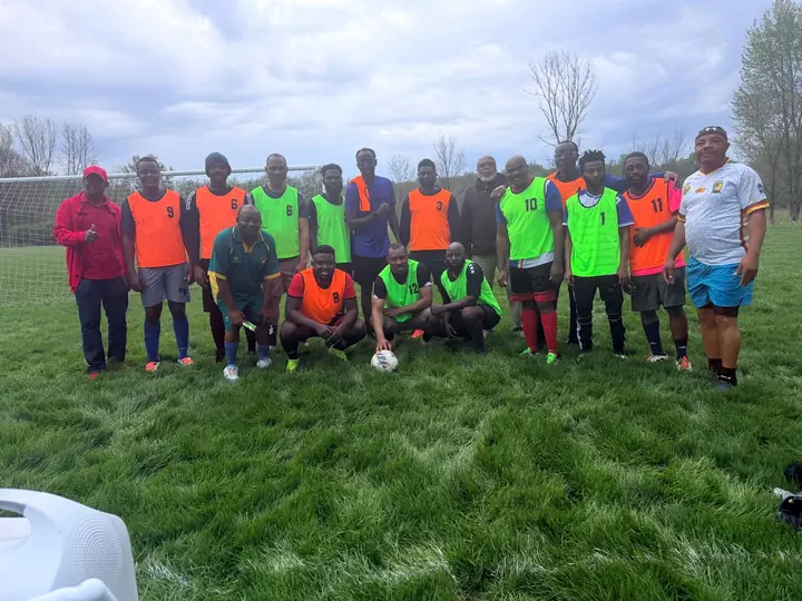 CAVFC members in orange and green bibs posing in front of the goal after training
